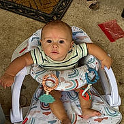 Weston joined the competition — help win amazing prizes! baby, child, infant, baby_seat, toys, striped_shirt, curious, indoors, floor, concrete, doormat, sandals, footwear, playful, looking_up, cute, small_hands, colorful, plastic_toys, seat
