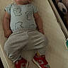 Weston is registered to the contest to win money with this photo: baby, baby_clothes, changing_table, child, childcare, cute, expression, face, footwear, indoor, infant, lying_down, onesie, red_sneakers, room, sleepwear, soft_lighting, sweatpants, teddy_bear, toy