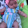 baby, infant, child, onesie, headband, pink_bow, striped_clothing, baby_chair, cartoon_background, colorful, socks, cute, chubby, cute_baby, indoors, soft_lighting, portrait, relaxed, baby_toys, playtime