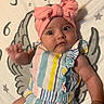Raelynn joined the competition — help win amazing prizes! baby, infant, headband, pink_bow, striped_outfit, colorful_clothing, laying_down, blanket, angel_wings, stars, curious_expression, wide_eyes, hand_raised, cute, child, indoors, portrait, soft_lighting, closeup, person