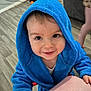 toddler, child, blue_robe, hooded_clothing, smile, indoor, floor, hand, face, eyes, person, baby, cute, wooden_floor, background, furniture, shelf, toy, home, playful