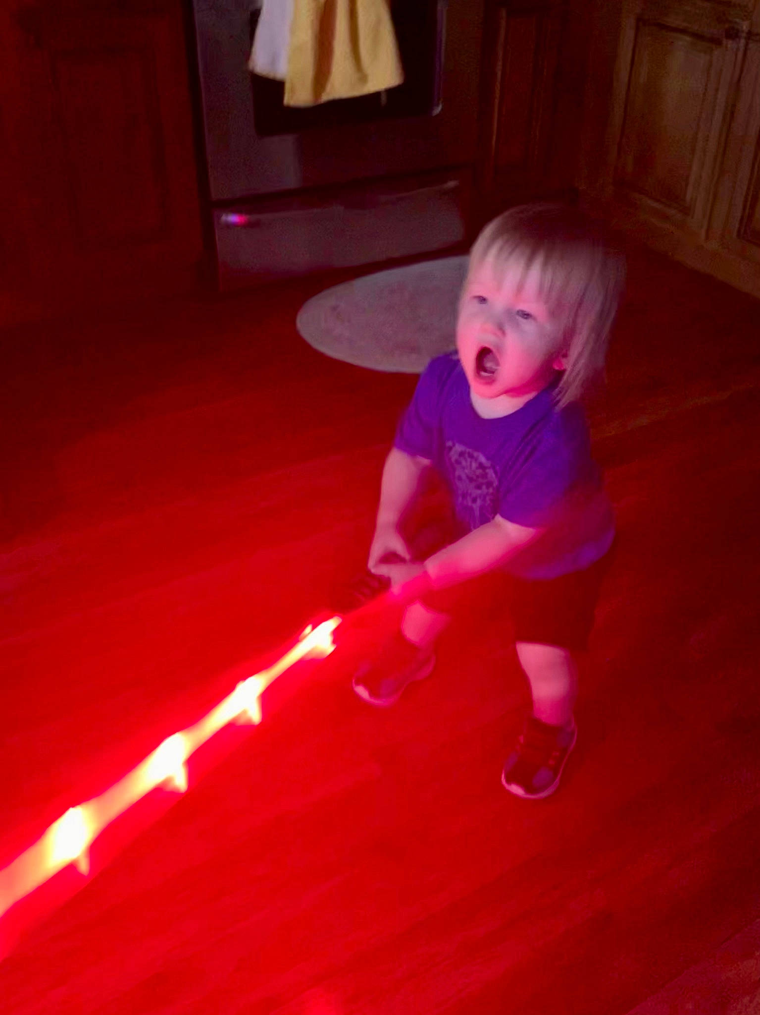 John is registered to the contest to win money with this photo: baby, baby_toddler_clothing, cabinetry, child, electric_blue, floor, flooring, fun, hardwood, human_leg, laminate_flooring, lamp, light, magenta, person, pink, purple, room, surprise, toddler