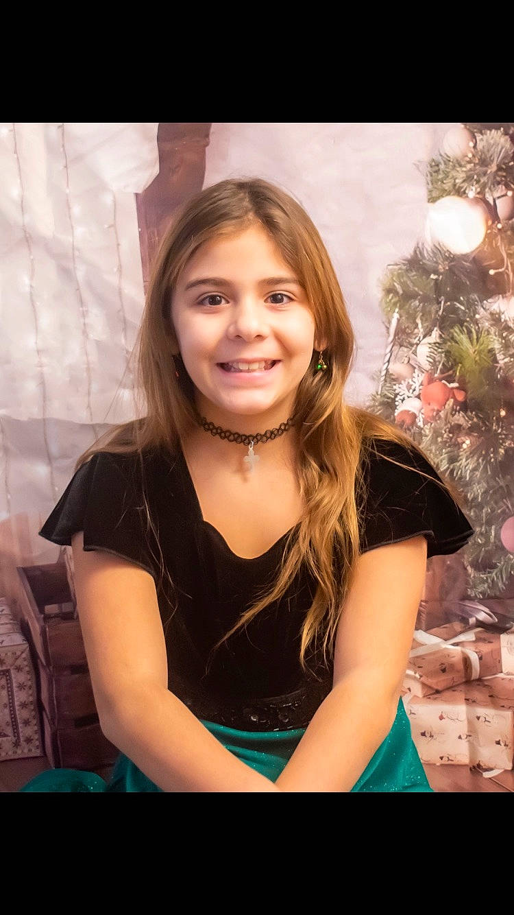 Isabella is registered to the contest to win money with this photo: brown_hair, christmas_tree, event, eyebrow, eyelash, flash_photography, fun, grass, happy, holiday, iris, jewellery, joy, long_hair, necklace, ornament, person, portrait_photography, sitting, smile