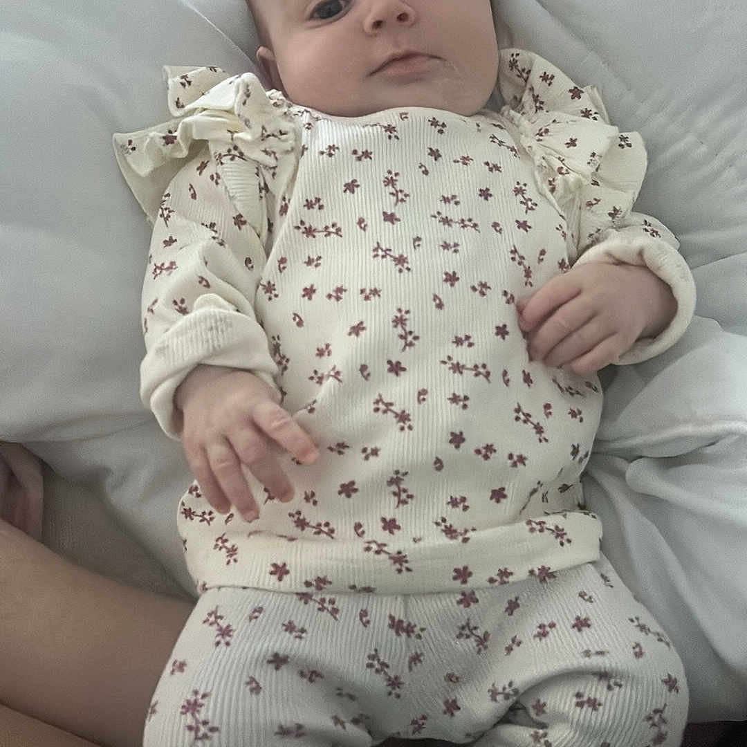 Ivie-Rose joined the competition — help win amazing prizes! baby, child, comfort, curious, cute, face, feet, floral_outfit, hands, head, indoor, infant, legs, lying_down, patterned_clothing, person, resting, sleepwear, soft, white_blanket
