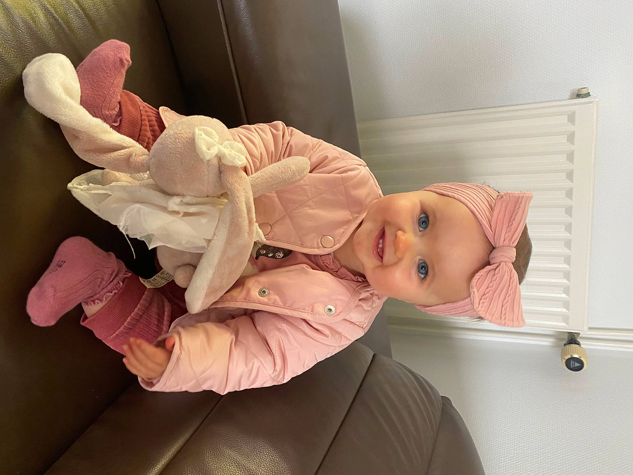 Romy participe au concours pour gagner de l'argent avec cette photo : baby, baby_products, baby_safety, baby_toddler_clothing, child, comfort, eye, eyelash, foot, gesture, hat, headwear, joy, knee, peach, person, pink, room, sitting, sleeve
