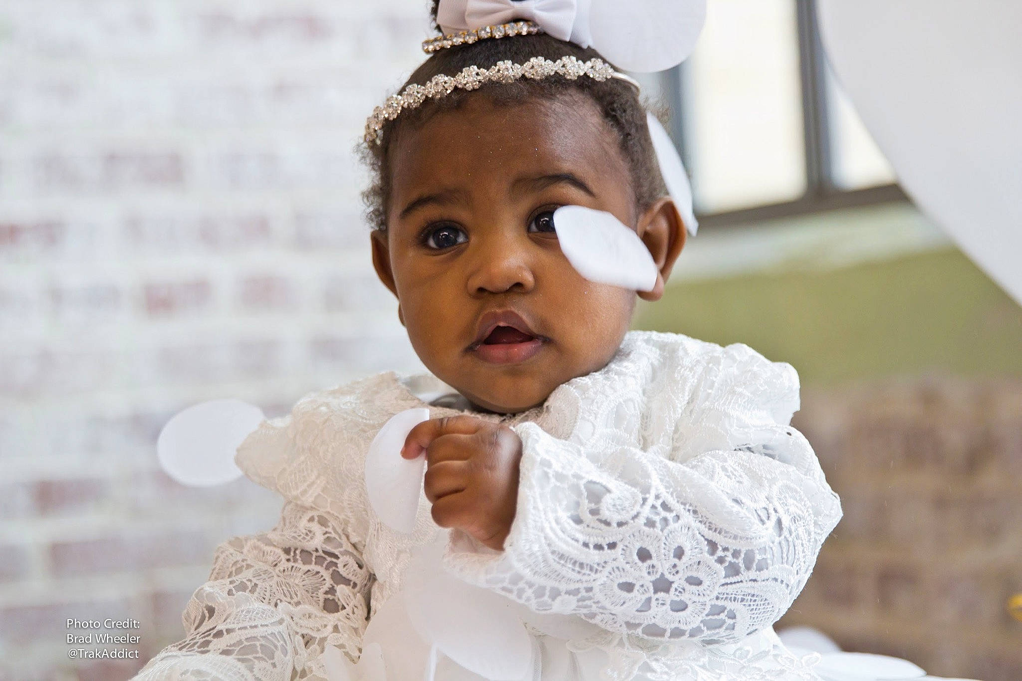 Zion is registered to the contest to win money with this photo: baby, ceremony, cheek, child, dress, fashion_accessory, forehead, hair_accessory, happy, head, headband, headgear, headpiece, lace, person, photography, ritual, skin, toddler, tradition