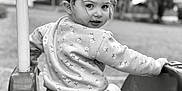 Aurora is registered to the contest to win money with this photo: child, toddler, playground, swing, outdoor, black_and_white, smiling, face, hair, clothing, seat, nature, trees, park, play, young, fun, person, casual, expression