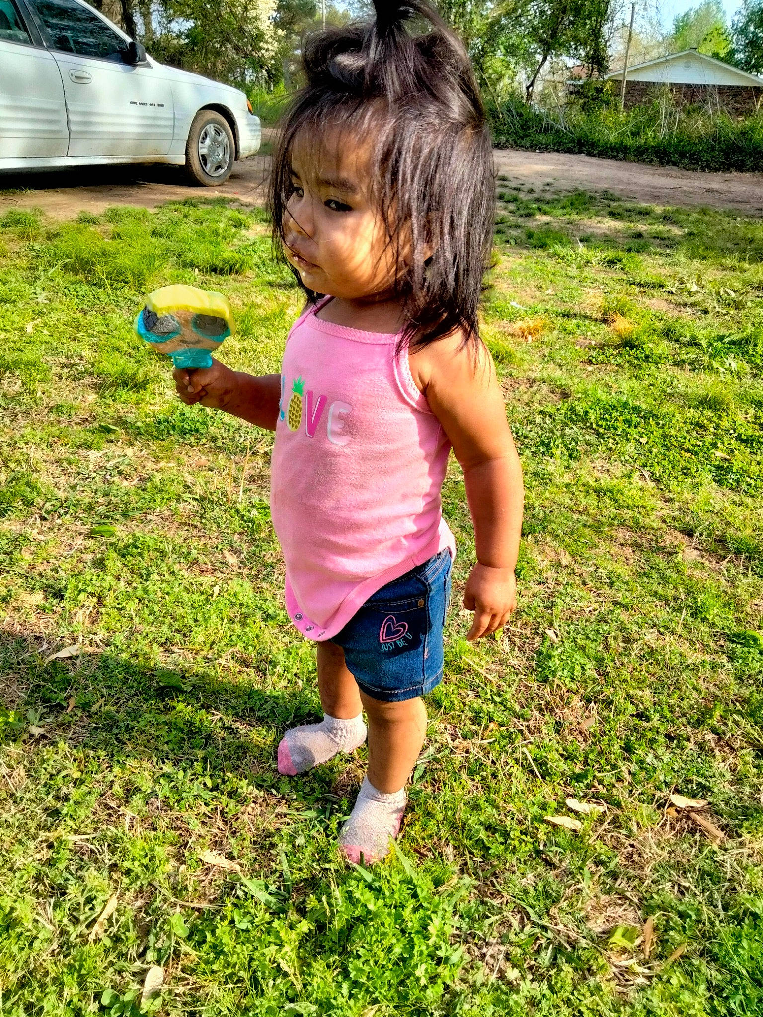 Malia is registered to the contest to win money with this photo: automotive_tire, botany, car, grass, grass_family, green, happy, lawn, leisure, mammal, people_in_nature, person, pink, plant, shorts, summer, tire, toddler, tree, vehicle