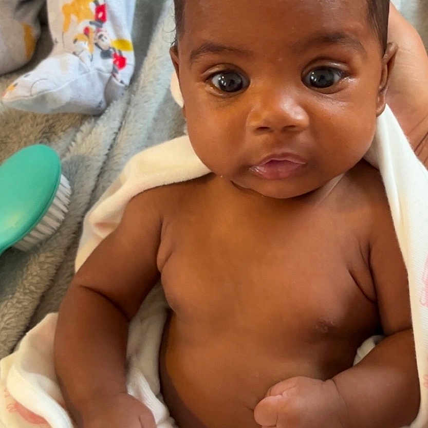 Jakiya Lyn is registered to the contest to win money with this photo: baby, blanket, brush, child, closeup, couch, cozy, curly_hair, face, fist, foot, hand, indoor, infant, pajamas, person, portrait, skin, soft_texture, wide_eyes