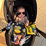 baby, infant, child, stroller, sunglasses, snack_bag, food, popcorn, outdoor, sunlight, pavement, tiles, portrait, sitting, 裸, feet, blanket, car_seat, fashion, funny