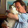Wallace participe au concours pour gagner de l'argent avec cette photo : man, cat, indoor, affection, holding, pet, portrait, closeup, casual_clothing, furniture, painting, table, water_bottle, relaxation, calm, domestic_life, human_animal_interaction, light_blue_shirt, whiskers, curious