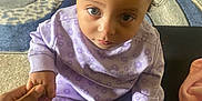 Mylah joined the competition — help win amazing prizes! toddler, child, baby, indoor, pajamas, purple, headband, bow, hand_holding, carpet, floor, person, curly_hair, socks, looking_up, cute, seated, adult_hand, cozy, soft_lighting