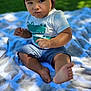 child, toddler, baby, sitting, blanket, outdoor, grass, shorts, shirt, foot, face, expression, sunlight, shadow, cute, curious, nature, daylight, skin, portrait
