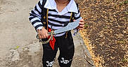Dominic joined the competition — help win amazing prizes! child, toddler, pirate, costume, hat, toy_sword, skull_pattern, striped_shirt, outdoor, sidewalk, residential_area, smiling, standing, portrait, full_body, playtime, dress_up, tree, grass, photography