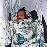newborn, baby, blanket, dinosaur_pattern, sleeping, infant, baby_carrier, cozy, soft_fabric, child, cute, resting, indoors, head, face, clothing, comfort, toddler, peaceful, portrait