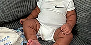 Emersyn is registered to the contest to win money with this photo: baby, infant, onesie, nike_logo, couch, gray_couch, baby_wipes, plastic_bag, indoors, child, sitting, chubby, cute, relaxed, portrait, skin, furniture, home, young_child, person