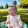 baby, crown, outdoor, grass, smiling, sunlight, blue_eyes, dress, blanket, nature, park, child, sitting, happy, infant, greenery, cute, portrait, daylight, young
