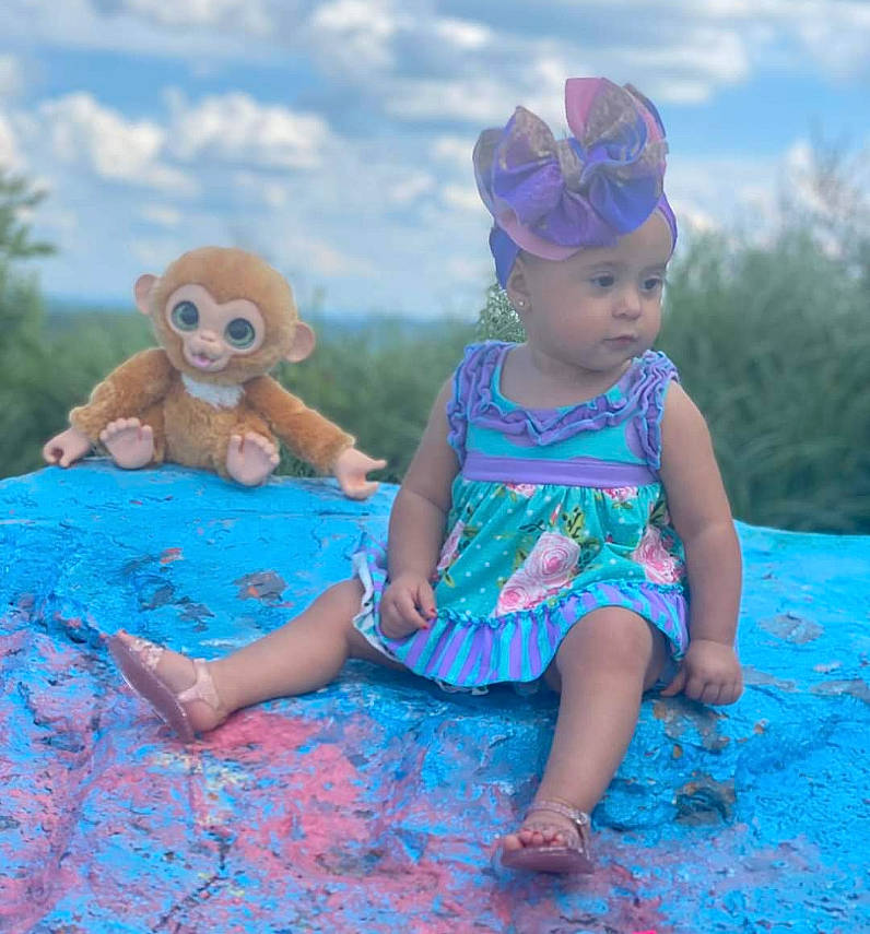 Tatiana is registered to the contest to win money with this photo: azure, baby_toddler_clothing, blue, cloud, dress, facial_expression, grass, happy, hat, head, headwear, leaf, leisure, mammal, organ, people_in_nature, person, pink, plant, sky