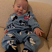 Waylen a rejoint le concours — aidez-le/la à gagner de superbes lots ! baby, beige_couch, child, couch, cozy, cute, fabric, hand, home_interior, infant, mickey_mouse, pajamas, portrait, relaxed, sitting, small_person, smile, socks, sweatshirt, toddler