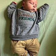 Néo a rejoint le concours — aidez-le/la à gagner de superbes lots ! baby, infant, sleeping, face, closed_eyes, gray_sweatshirt, printed_text, beige_pants, gray_socks, lying_on_bed, mint_sheet, peaceful, newborn, cute, cozy, portrait, soft_lighting, hands_up, skin, sleeping_baby