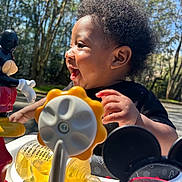 Jiquavious is registered to the contest to win money with this photo: baby, black_clothing, child, colorful, curly_hair, daylight, hand, happy, infant, mickey_mouse, nature, outdoor, park, plastic_toy, playtime, profile, smiling, sunlight, toy, trees