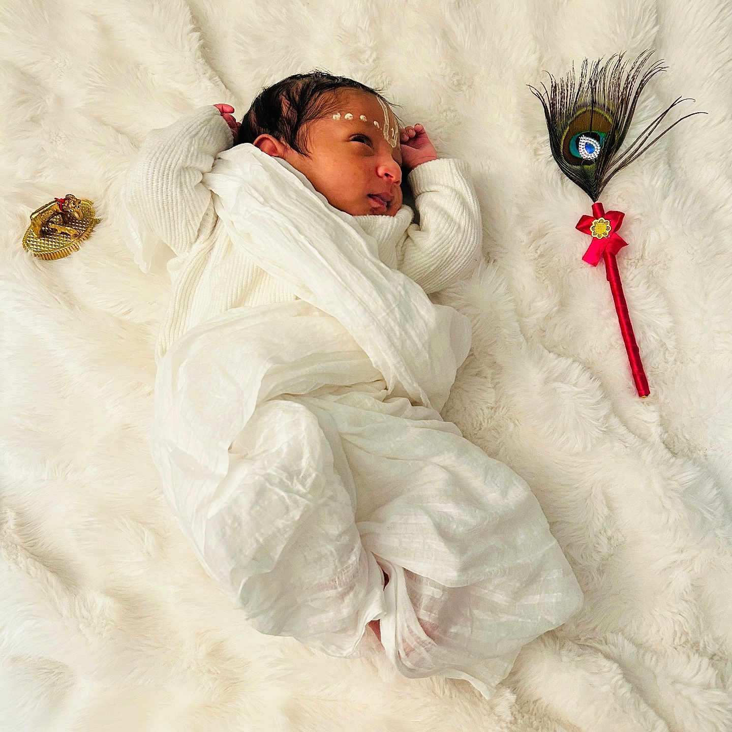 Vedant joined the competition — help win amazing prizes! baby, closeup, cozy, cultural, cute, face_markings, golden_ornament, indoor, infant, newborn, peaceful, peacock_feather, portrait, resting, sleeping, small_hands, soft_texture, tender_moment, white_blanket, wrapped_in_cloth