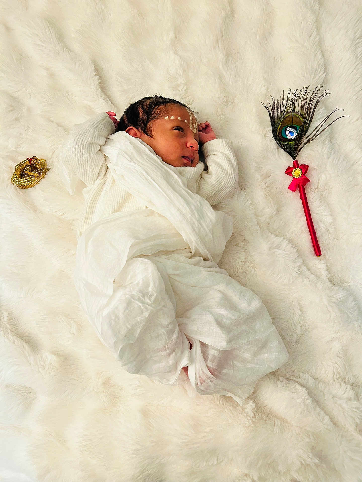 Vedant joined the competition — help win amazing prizes! newborn, baby, infant, white_blanket, soft_texture, peacock_feather, golden_ornament, face_markings, sleeping, wrapped_in_cloth, cultural, peaceful, closeup, indoor, portrait, cute, small_hands, resting, cozy, tender_moment