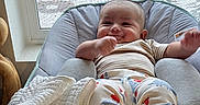 Aziel is registered to the contest to win money with this photo: baby, baby_chair, baby_garment, blanket, clothing, comfort, cushion, face, footwear, happy, home, indoor, infant, natural_light, person, seated, smiling, window, window_screen, winter_outside
