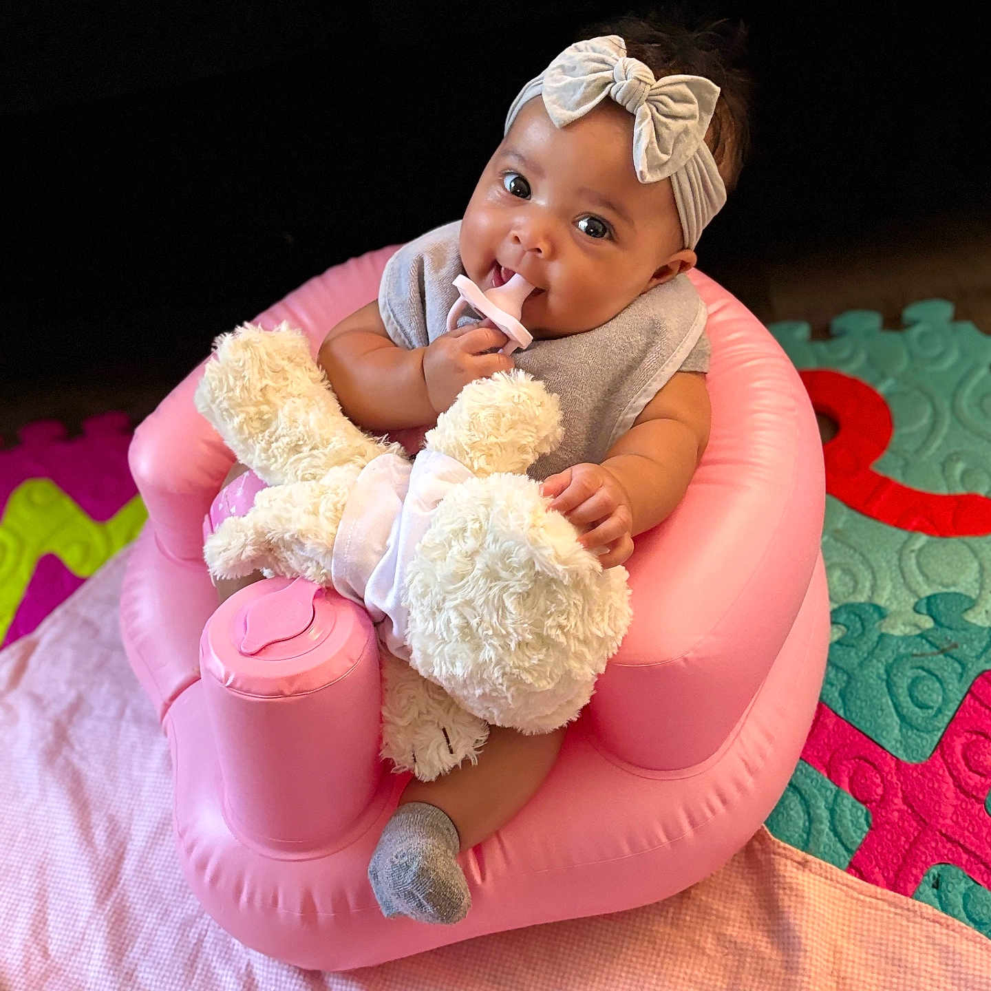 Ymiri Noelle joined the competition — help win amazing prizes! adorable, baby, blanket, bow, chewing, child, chubby_cheeks, cute, headband, indoor, infant, pacifier, person, pink_inflatable_chair, play_mat, seated, smiling, sock, soft_toy, teddy_bear