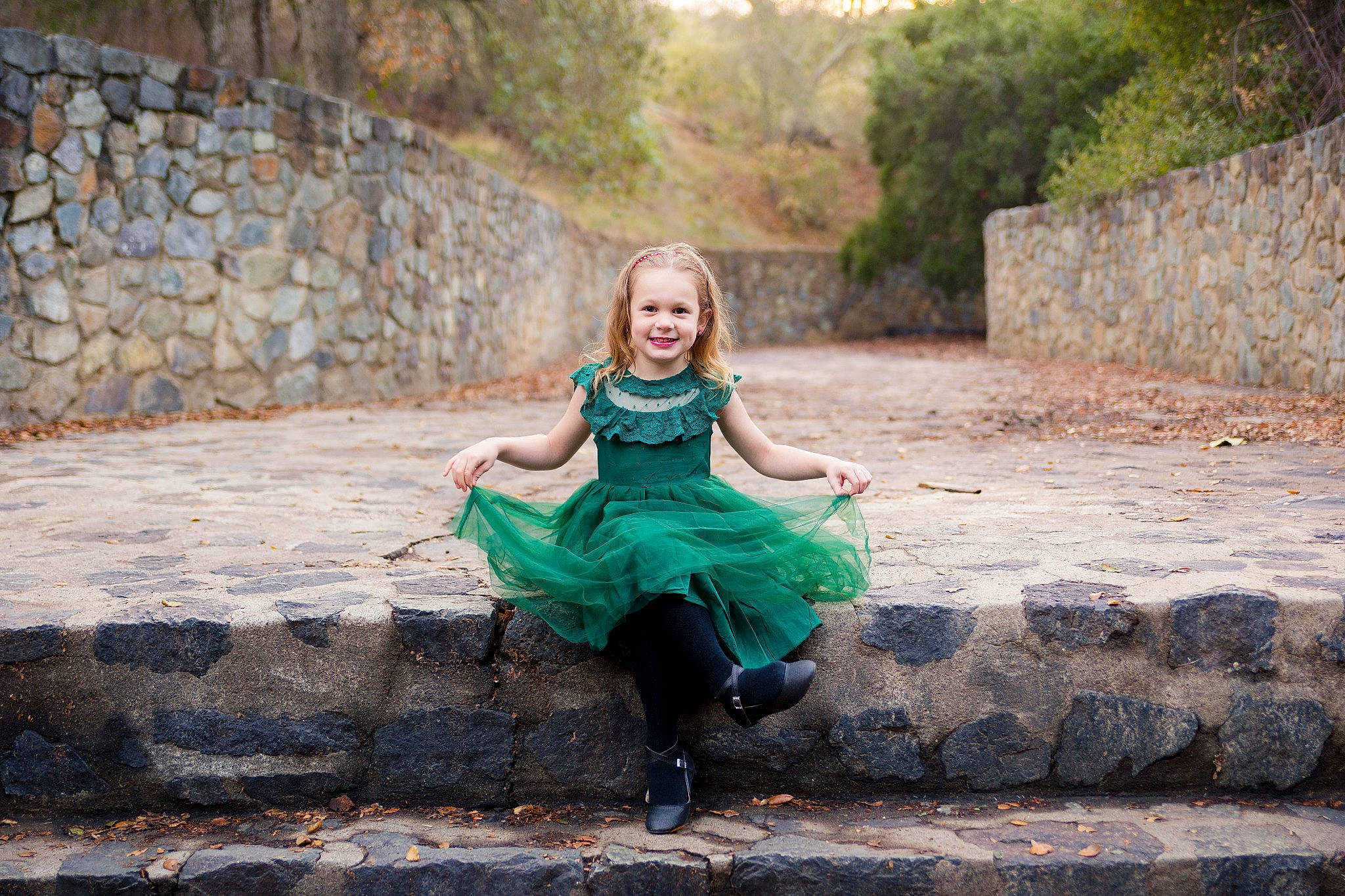 Caylee is registered to the contest to win money with this photo: beauty, blond, child, dress, eye, fun, green, joy, lady, leisure, people, person, photo_shoot, photograph, photography, rock, sitting, smile, stone_wall, tree
