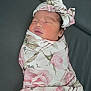 Jayda is registered to the contest to win money with this photo: newborn, baby, sleeping, swaddled, blanket, floral, headband, bow, face, closed_eyes, skin, peaceful, infant, resting, portrait, indoor, soft, cute, child, leather_surface