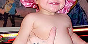 Anna joined the competition — help win amazing prizes! toddler, baby, pink_bonnet, smile, diaper, tattoo, hand, indoor, poster, wall_art, light_strip, happy, child, person, skin, cute, expression, portrait, holding, room