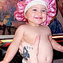toddler, baby, pink_bonnet, smile, diaper, tattoo, hand, indoor, poster, wall_art, light_strip, happy, child, person, skin, cute, expression, portrait, holding, room