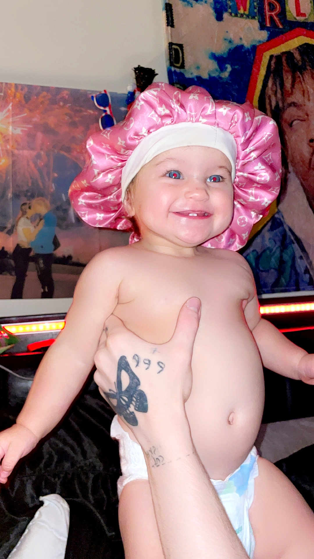 Anna joined the competition — help win amazing prizes! toddler, baby, pink_bonnet, smile, diaper, tattoo, hand, indoor, poster, wall_art, light_strip, happy, child, person, skin, cute, expression, portrait, holding, room