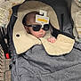 baby, stroller, sunglasses, shopping_cart, blanket, infant, child, clothing, retail, store, person, headwear, cozy, cute, indoor, accessory, face, hand, fabric, shopping