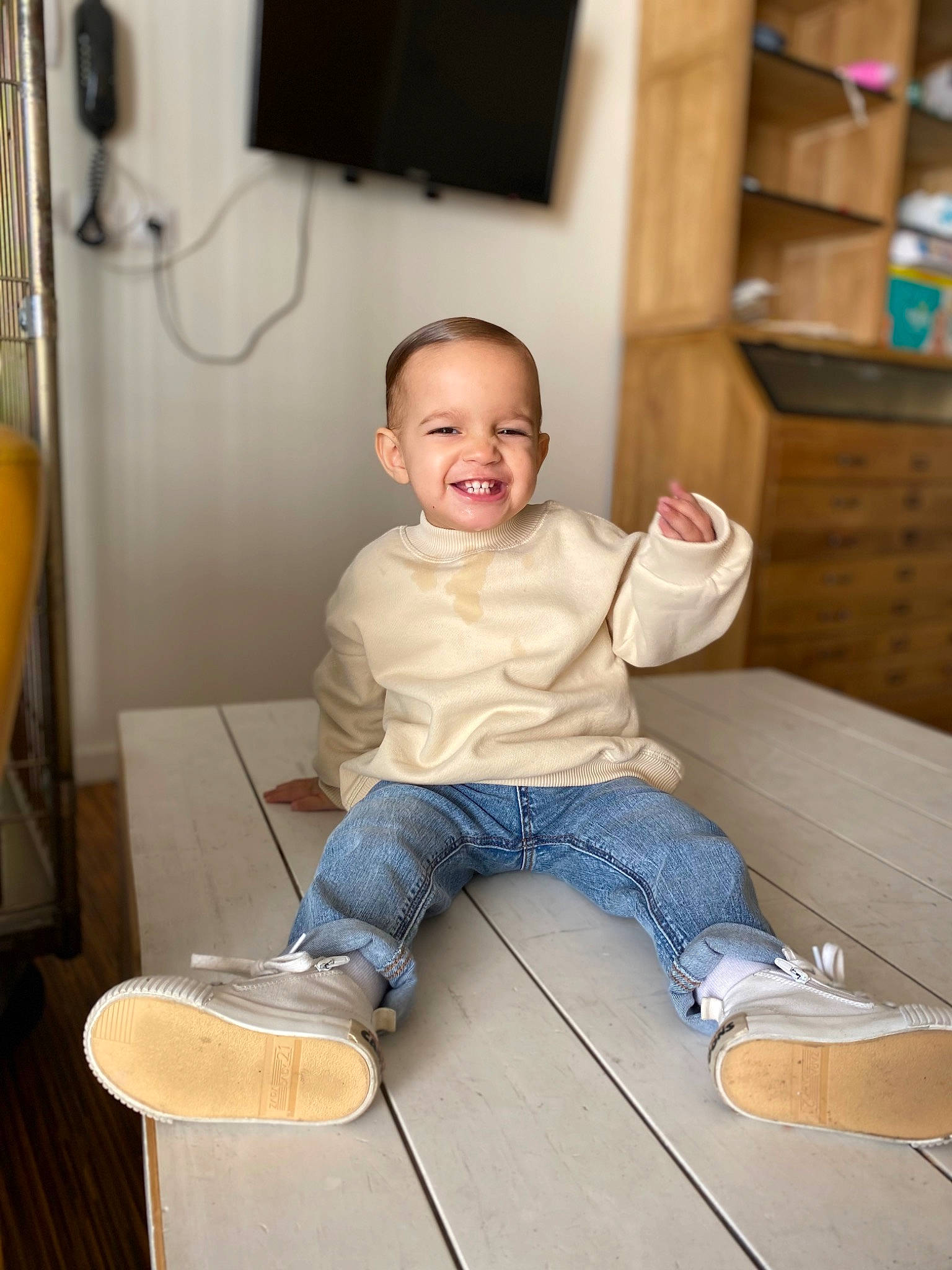 Issa a rejoint le concours — aidez-le/la à gagner de superbes lots ! baby_toddler_clothing, chair, child, comfort, floor, flooring, hardwood, joy, knee, leg, person, picture_frame, shelf, sitting, smile, sneakers, standing, t_shirt, television, toddler