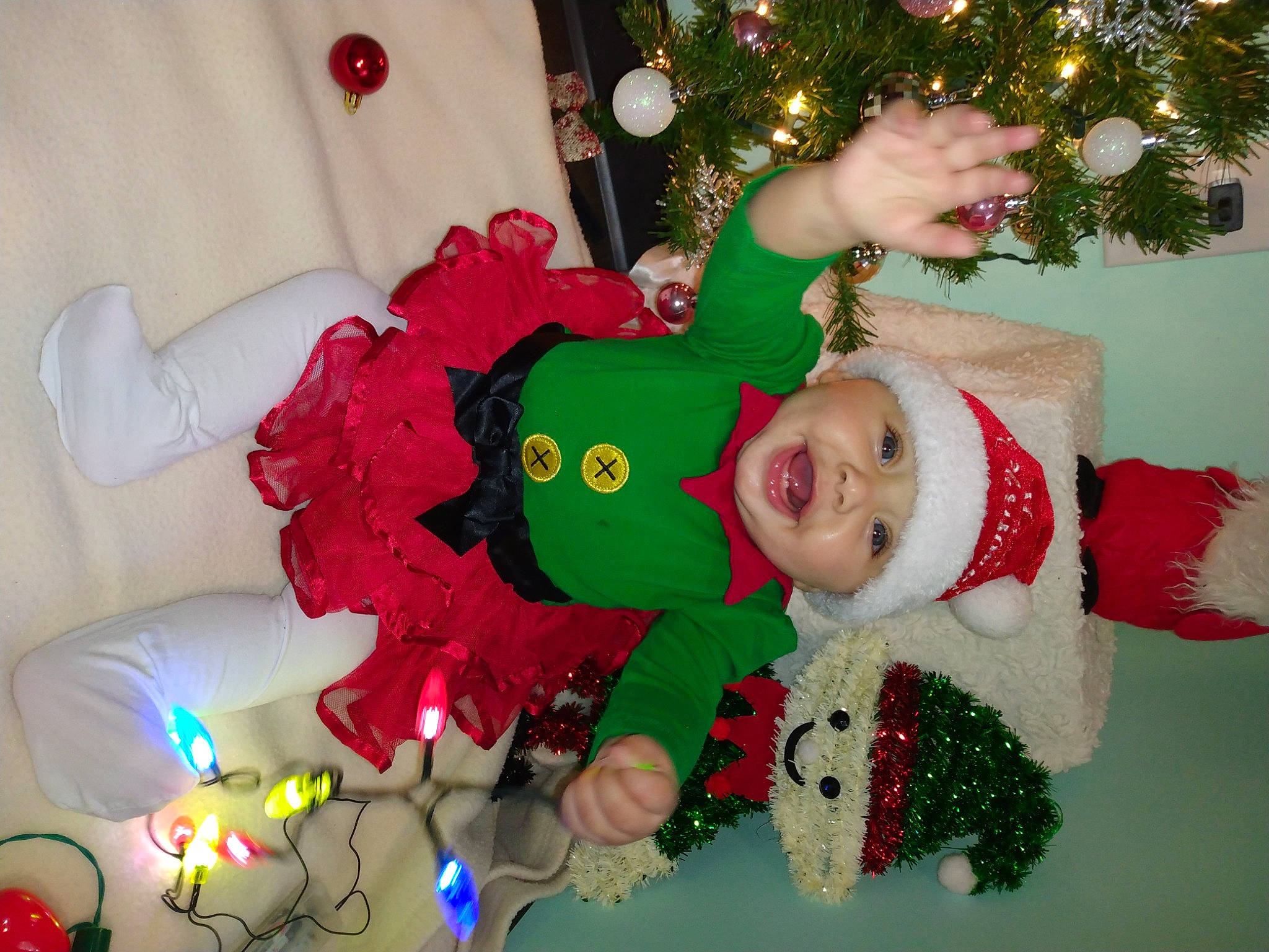 Georgia is registered to the contest to win money with this photo: child, christmas, christmas_decoration, christmas_eve, christmas_ornament, christmas_tree, event, fictional_character, fun, green, happy, headwear, holiday, holiday_ornament, lap, person, plant, red, santa_claus, smile
