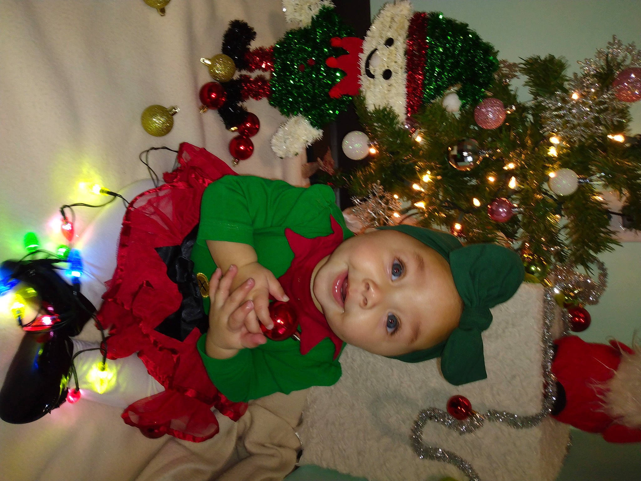 Georgia joined the competition — help win amazing prizes! baby, christmas, christmas_decoration, christmas_eve, christmas_ornament, christmas_tree, event, fun, green, happy, headwear, holiday, holiday_ornament, lap, ornament, person, plant, room, smile, toddler