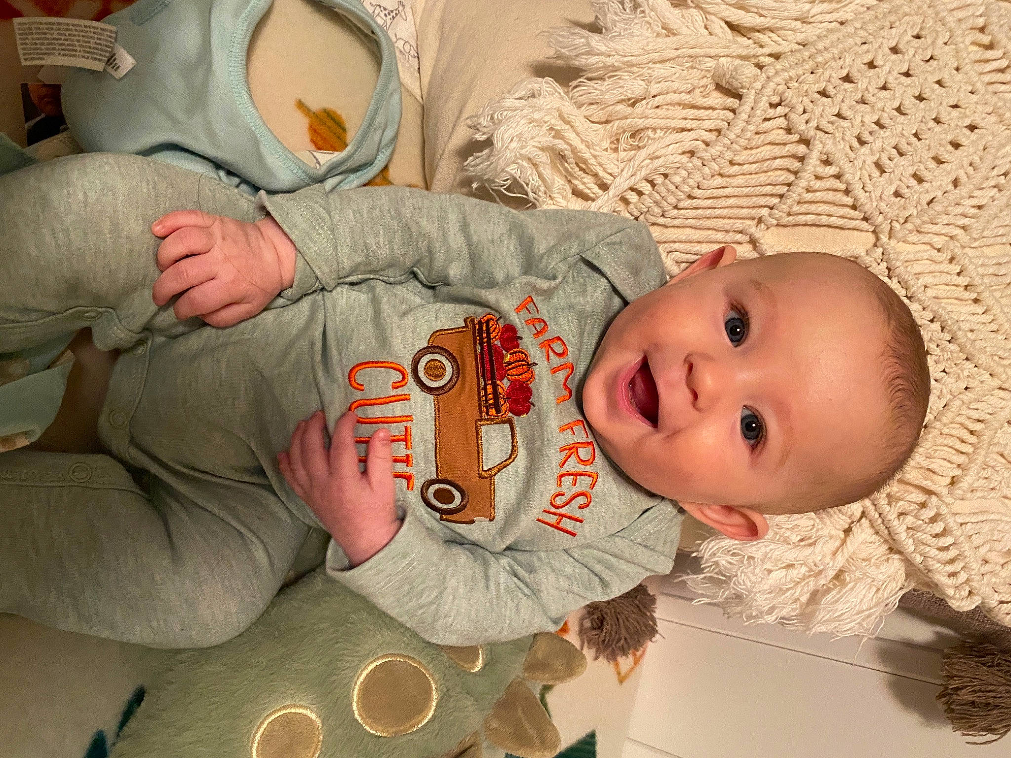 John is registered to the contest to win money with this photo: baby, baby_products, baby_safety, baby_toddler_clothing, cheek, child, comfort, happy, human_body, linens, mouth, pattern, person, room, sitting, skin, sleeve, smile, toddler, wood