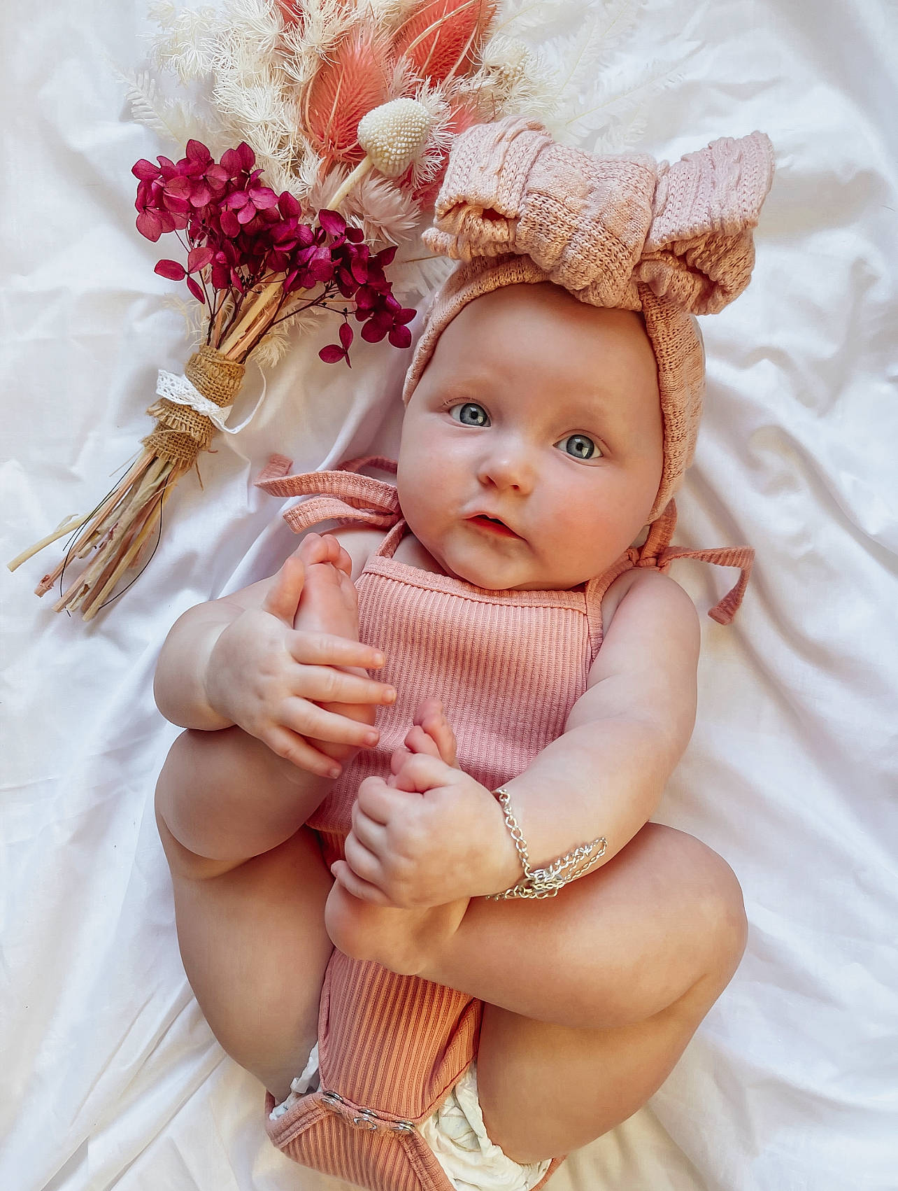 Hadleigh is registered to the contest to win money with this photo: baby, baby_toddler_clothing, child, eye, eyelash, finger, flower, hand, head, headband, headpiece, headwear, nail, person, petal, pink, plant, skin, textile, thigh