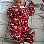 baby, blanket, child, cozy, cute, hat, holiday_theme, indoor, infant, lying_down, newborn, onesie, peaceful, red_clothing, reindeer_pattern, resting, sleeping, smiling, soft_fabric, warm_clothing