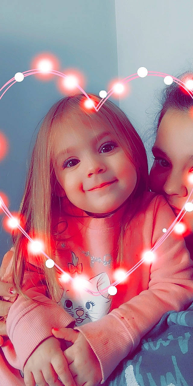 Londyn is registered to the contest to win money with this photo: christmas_ornament, eye, face, flash_photography, gesture, hair, happy, head, human_body, iris, joy, light, lighting, lip, organ, person, photograph, pink, skin, smile