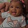Armani Grace is registered to the contest to win money with this photo: baby, smiling, indoor, blanket, clothing, hair_bows, cute, child, portrait, infant, happy, screenshot, video_player, phone_screen, text, playback_controls, soft_texture, pink, white_shirt, cozy
