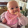 baby, child, bib, pink, cracker, highchair, indoor, smiling, face, hand, sweater, furniture, plant, lamp, table, living_room, person, cute, eating, home