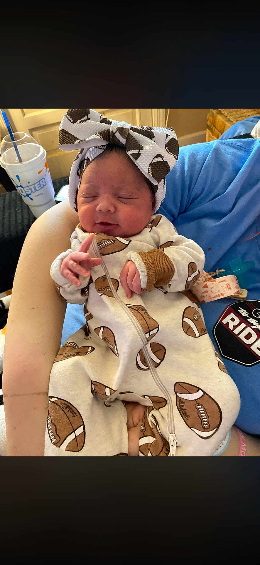 Wynter joined the competition — help win amazing prizes! baby, newborn, infant, headband, bow, onesie, football_print, eyes_closed, sleeping, hand, arm, caregiver, cup_with_straw, blanket, indoor, cozy, portrait, zipper, pattern, clothing