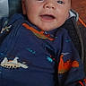baby, child, infant, smiling, happy, portrait, face, sitting, car_seat, clothing, dinosaur_print, blue_outfit, orange, indoor, vehicle, seatbelt, harness, closeup, looking_at_camera, colorful