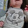 baby, child, infant, smiling, laughing, face, portrait, car_seat, vehicle, safety_label, mickey_mouse, clothing, onesie, blanket, seated, indoor, close_up, happy, hand, photography