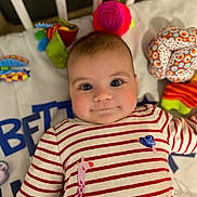 éléna a rejoint le concours — aidez-le/la à gagner de superbes lots ! baby, infant, striped_shirt, giraffe_print, bird_print, toys, crib, blanket, smiling, face, child, cute, colorful, plush_toy, red, white, patterned_clothing, lying_down, indoors, portrait