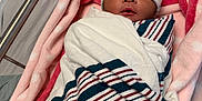 Amira is registered to the contest to win money with this photo: newborn, baby, hospital, blanket, bassinet, hat, sleeping, pink, congratulations_card, cozy, wrapped, infant, cute, resting, soft, striped_blanket, medical, bed, child, person