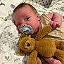 baby, pacifier, blanket, teddy_bear, soft_toy, infant, bedtime, sleeping_area, cute, cozy, child, face, hand, clothing, plush, portrait, indoors, comfort, resting, newborn